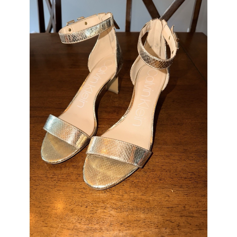 Calvin Klein gold strap sandals featuring a python print and a back zipper
